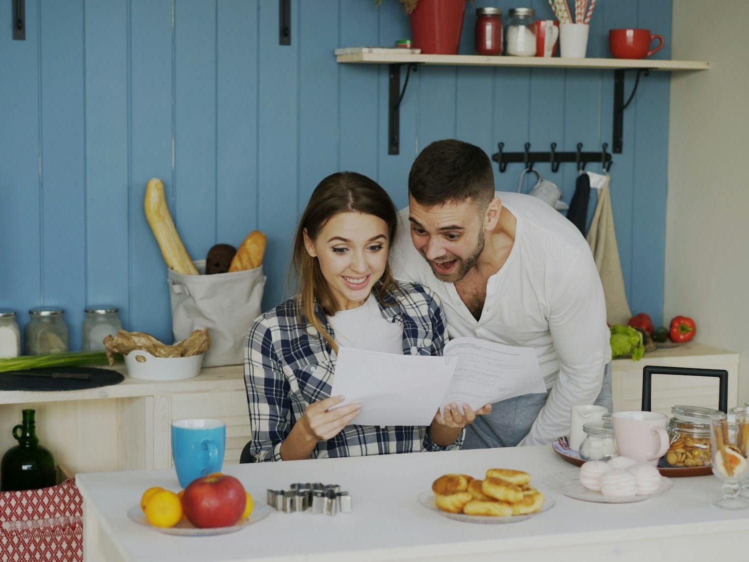 Couple at the kitchen table smiling over a letter