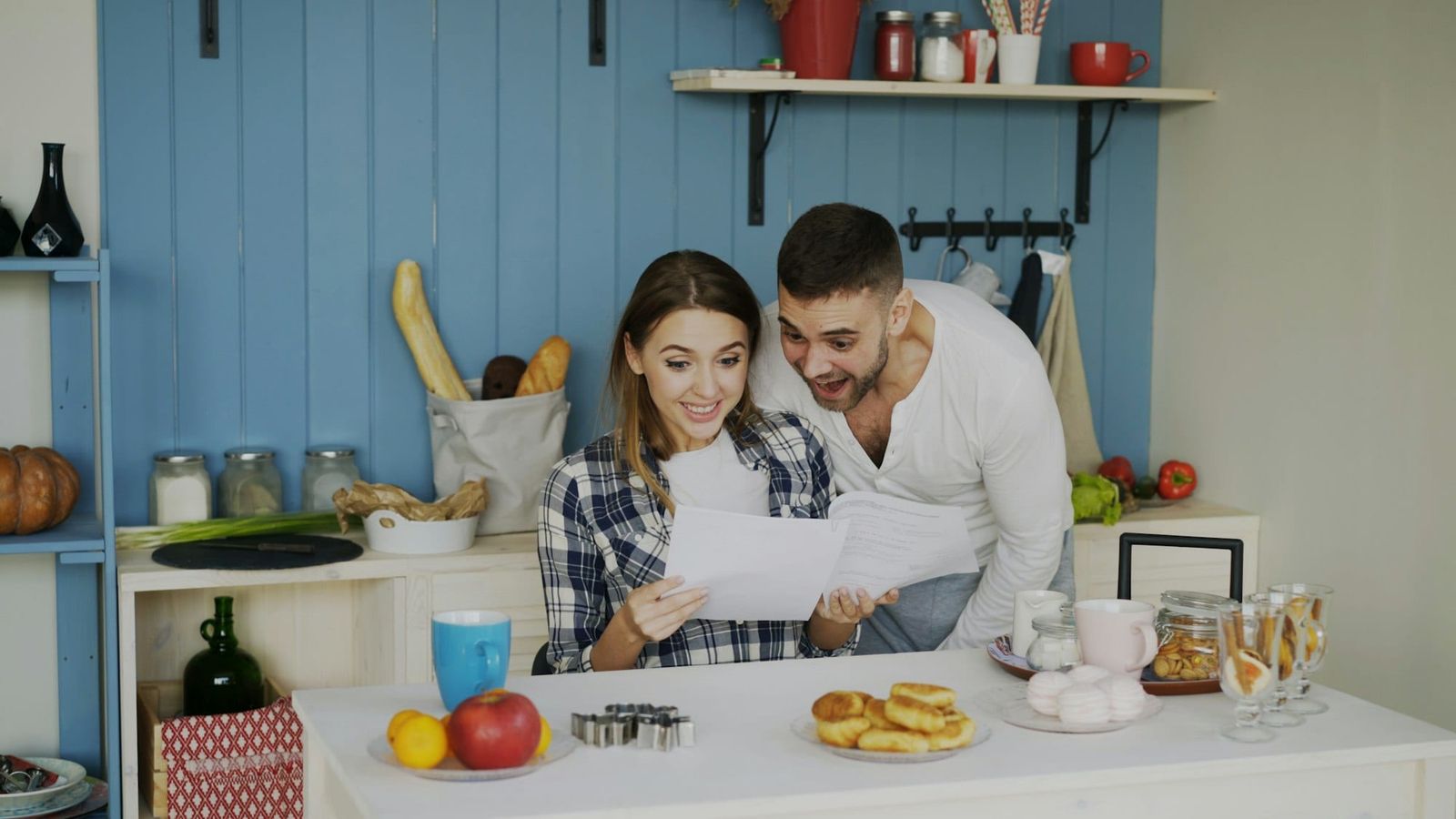 Couple at the kitchen table smiling over a letter